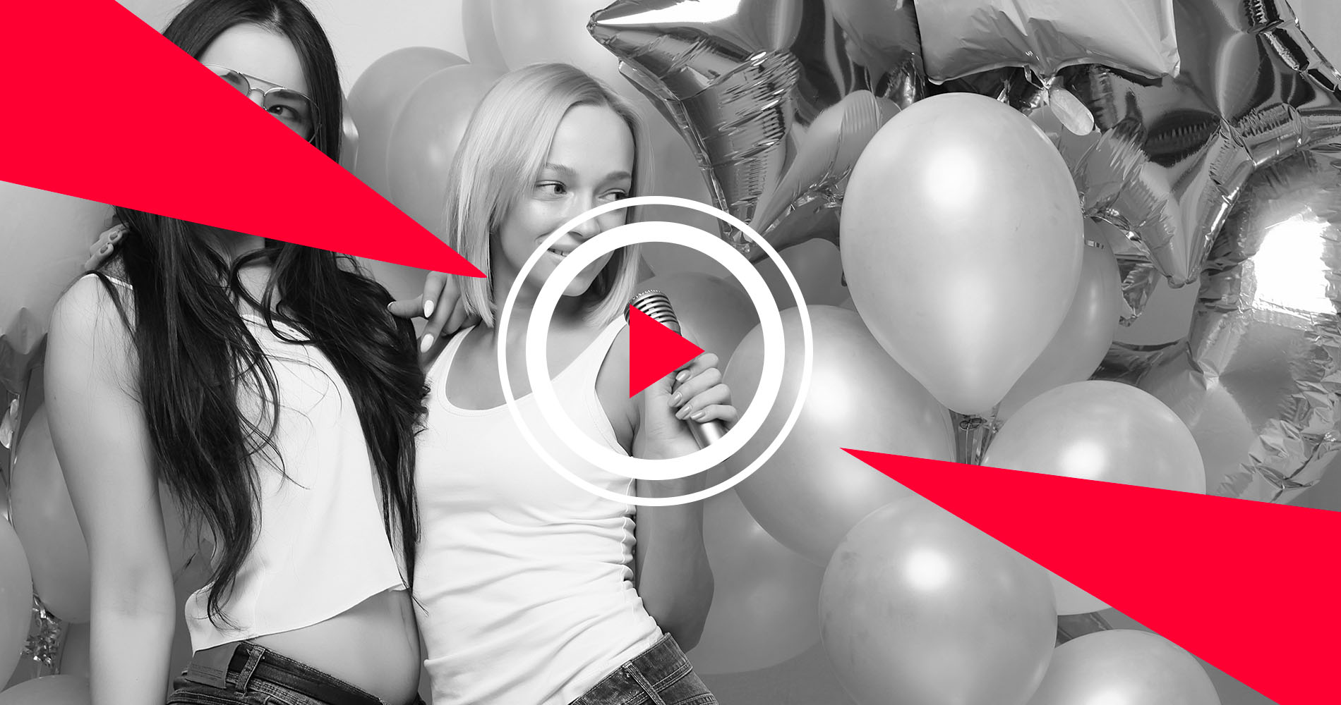 Two women singing amid party balloons